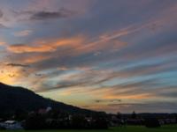 Langgezogene Wolkenschleier beginnen orangerot zu leuchten